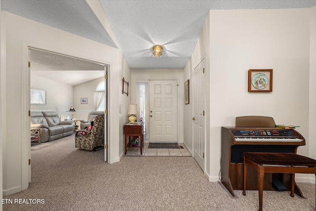 foyer with light carpet, a textured ceiling, and baseboards