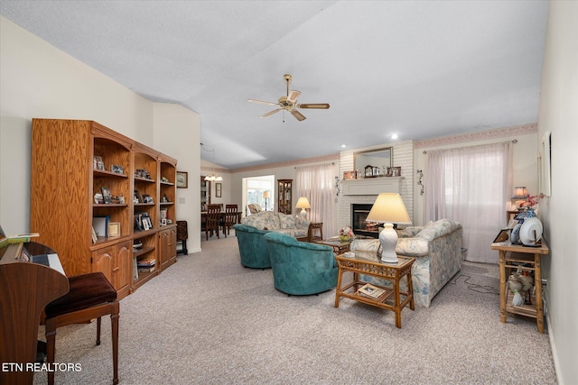 carpeted living room with a brick fireplace, vaulted ceiling, and a ceiling fan