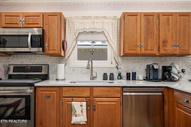 kitchen with a sink, stainless steel appliances, light countertops, and brown cabinets