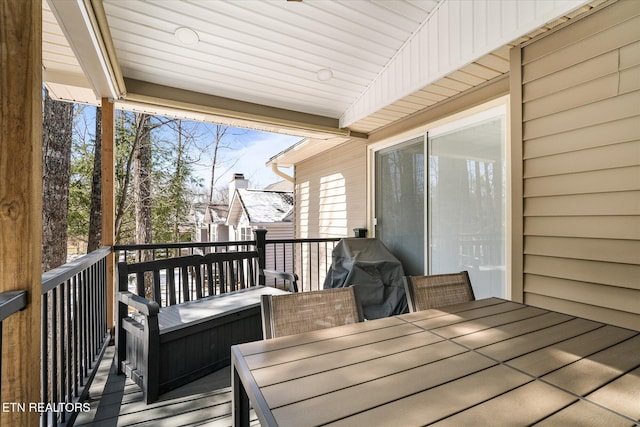 wooden terrace with outdoor dining area and grilling area