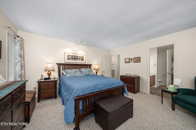 bedroom with light carpet, ensuite bath, visible vents, and a textured ceiling