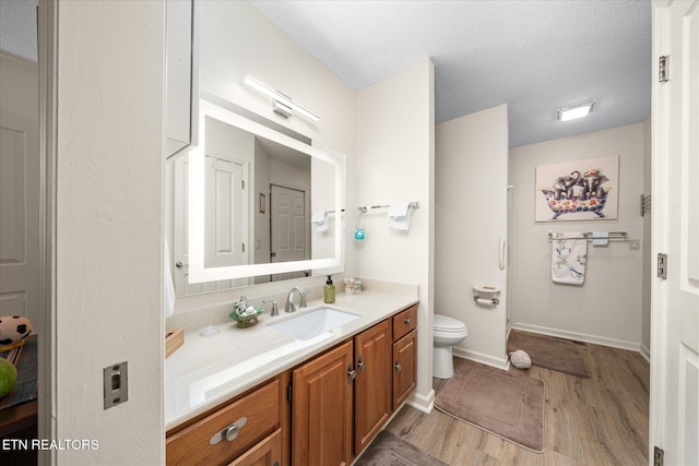 full bathroom featuring a closet, toilet, a textured ceiling, vanity, and wood finished floors