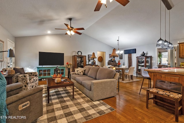 living room with dark wood-type flooring, ceiling fan with notable chandelier, and vaulted ceiling