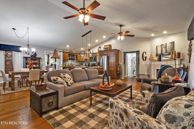 living room with high vaulted ceiling, dark hardwood / wood-style floors, ceiling fan with notable chandelier, and a textured ceiling