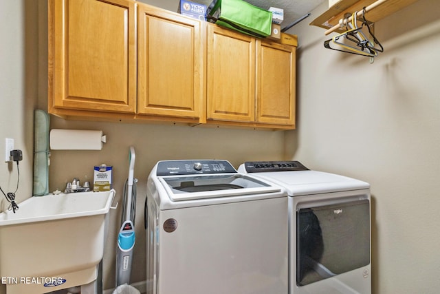 clothes washing area with cabinets, washer and clothes dryer, and sink