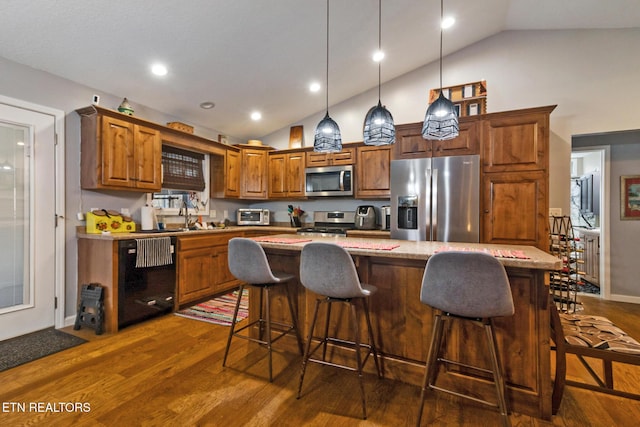 kitchen featuring pendant lighting, stainless steel appliances, dark hardwood / wood-style floors, a center island, and light stone counters