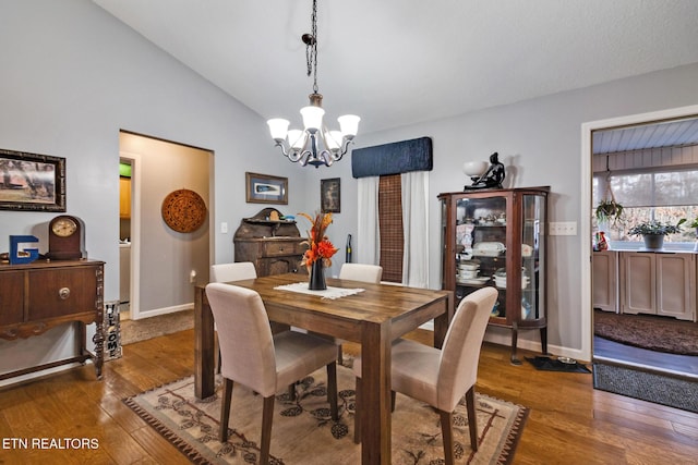 dining area with lofted ceiling, dark hardwood / wood-style floors, and a notable chandelier