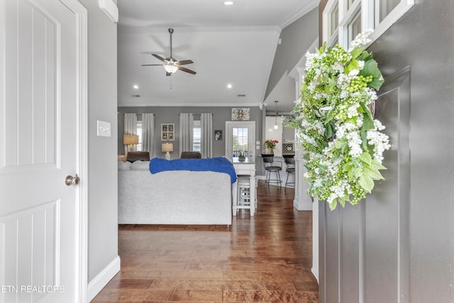 living room with dark wood-type flooring, vaulted ceiling, crown molding, and ceiling fan