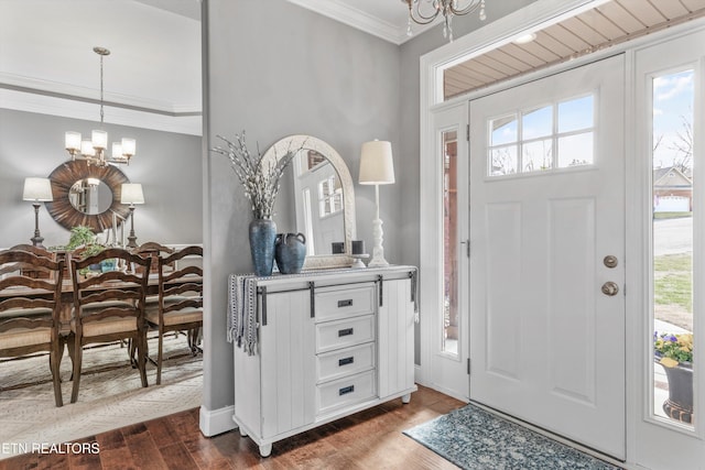 entrance foyer featuring dark hardwood / wood-style flooring, crown molding, and an inviting chandelier