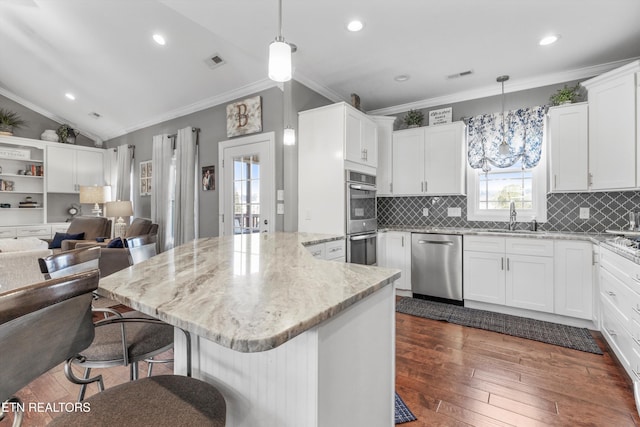 kitchen with appliances with stainless steel finishes, white cabinets, and hanging light fixtures