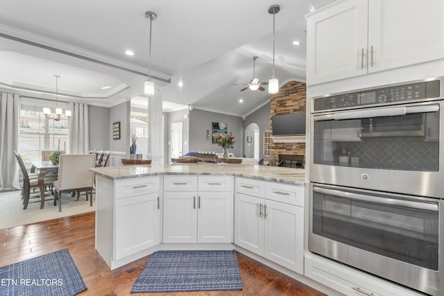 kitchen with white cabinetry, kitchen peninsula, double oven, and decorative light fixtures