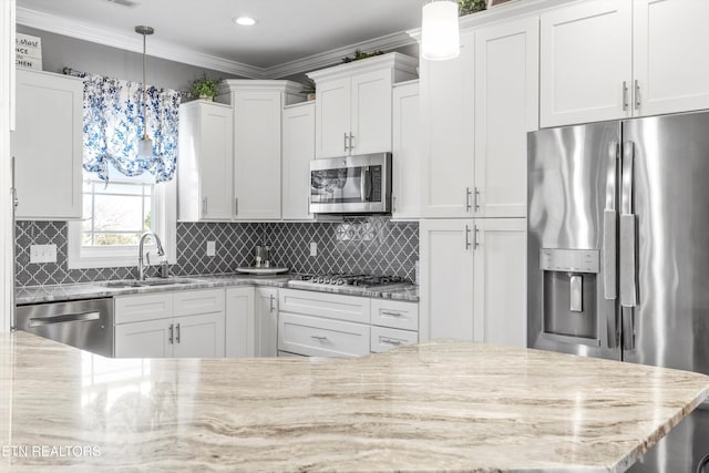 kitchen featuring stainless steel appliances, light stone counters, pendant lighting, sink, and white cabinetry