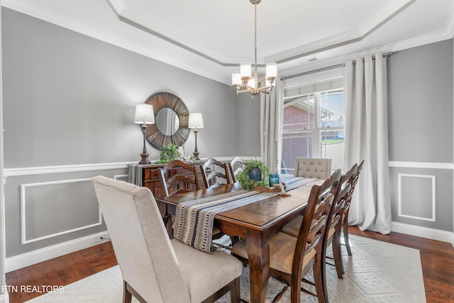 dining room featuring a chandelier, a tray ceiling, dark hardwood / wood-style flooring, and ornamental molding