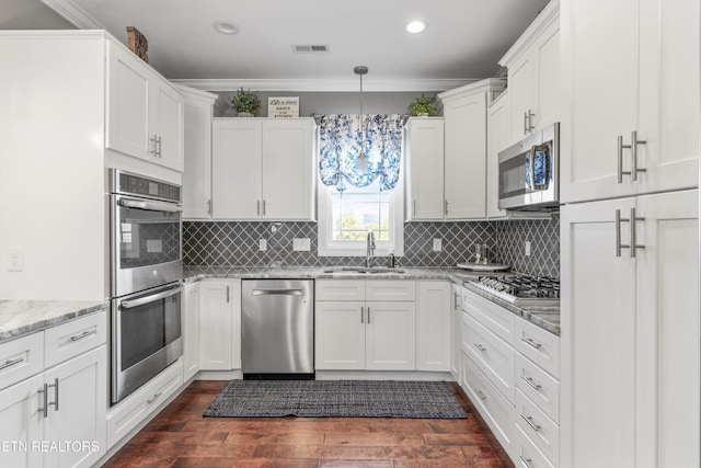 kitchen featuring decorative light fixtures, sink, light stone counters, appliances with stainless steel finishes, and white cabinets