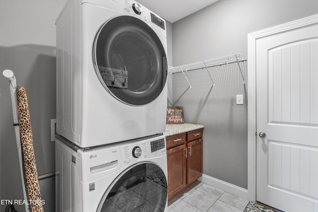 washroom with cabinets, light tile patterned floors, and stacked washer / drying machine