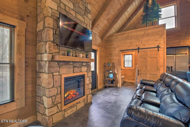 living room with a fireplace, wood walls, beamed ceiling, wood ceiling, and a barn door