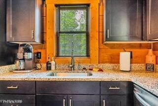 kitchen featuring light stone counters, dishwasher, sink, and dark brown cabinets