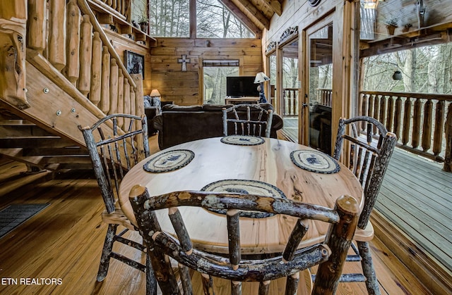 dining room featuring hardwood / wood-style floors, high vaulted ceiling, and wood walls