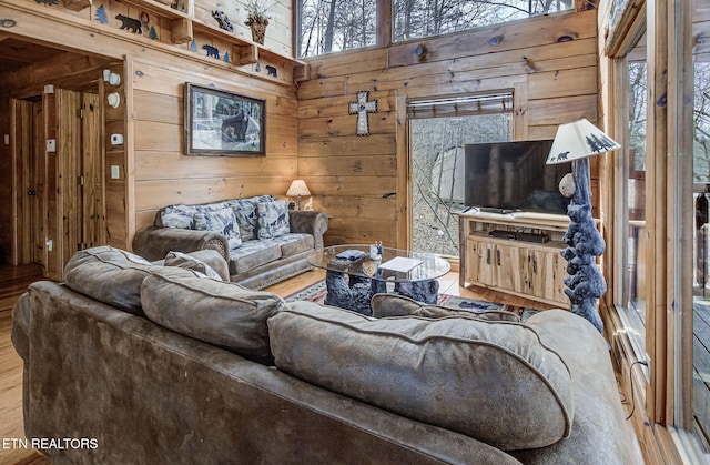living room featuring hardwood / wood-style flooring, a towering ceiling, and wood walls