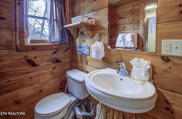 bathroom featuring sink, toilet, and wood walls