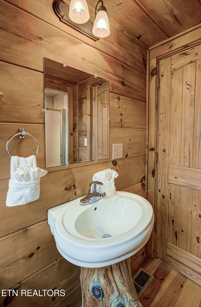 bathroom with wood ceiling, wooden walls, sink, and hardwood / wood-style floors