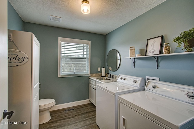 clothes washing area with sink, washer and dryer, dark hardwood / wood-style floors, and a textured ceiling