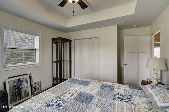 bedroom with a closet, ceiling fan, and a raised ceiling