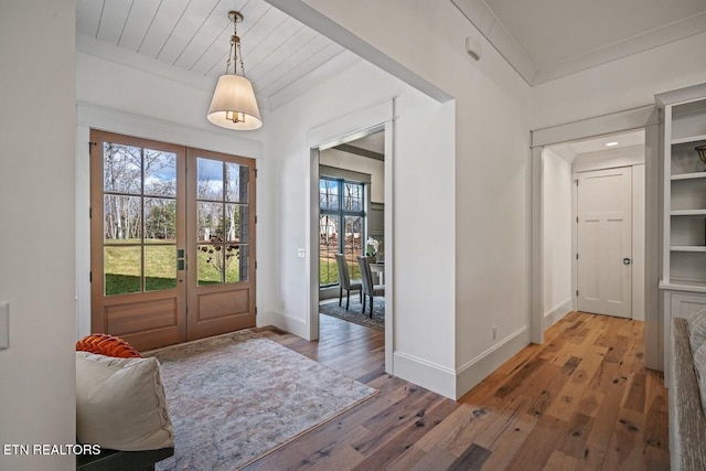 entrance foyer with hardwood / wood-style flooring, ornamental molding, and french doors