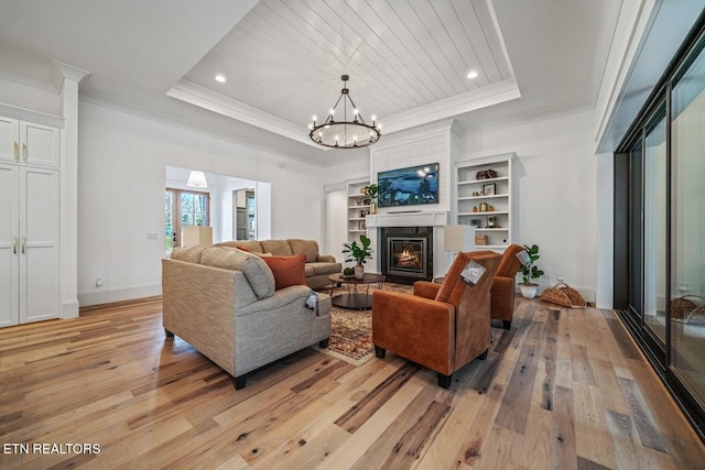 living room with crown molding, light hardwood / wood-style flooring, and a tray ceiling