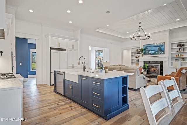 kitchen with stainless steel dishwasher, a wealth of natural light, an island with sink, and white cabinets