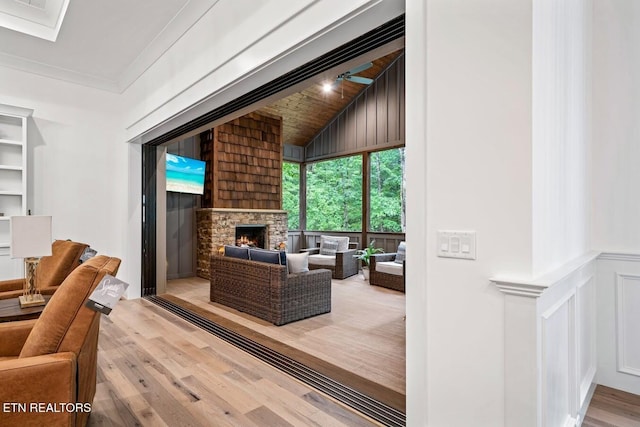 living room with ornamental molding, lofted ceiling, hardwood / wood-style floors, and a fireplace