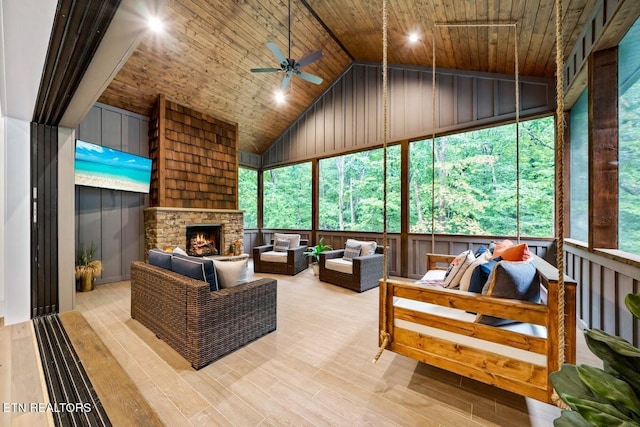 sunroom / solarium with lofted ceiling, a stone fireplace, wooden ceiling, and ceiling fan