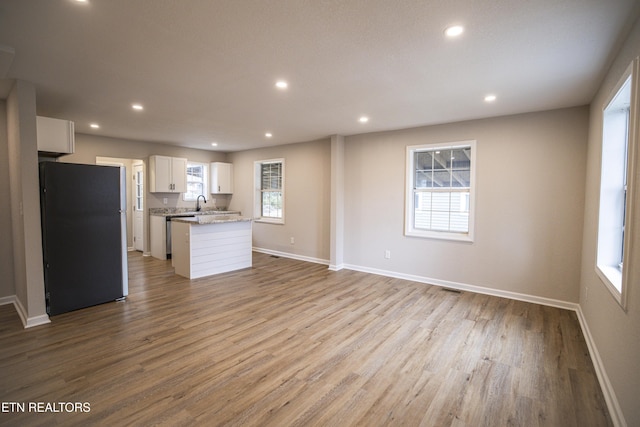 kitchen with white cabinetry, light wood-type flooring, stainless steel refrigerator, and a healthy amount of sunlight