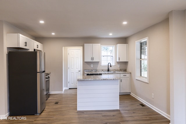 kitchen featuring sink, white cabinetry, a kitchen island, stainless steel appliances, and light stone countertops