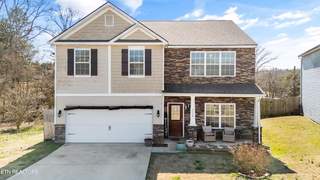 craftsman-style home with a porch, concrete driveway, fence, a garage, and a front lawn