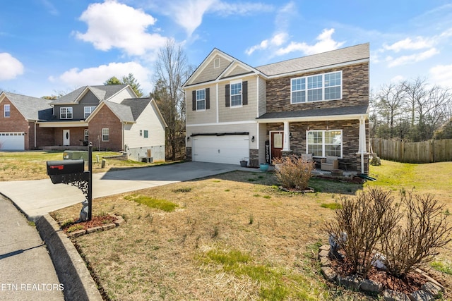 view of front of property featuring a garage, concrete driveway, stone siding, fence, and a front lawn