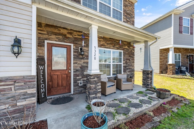 view of exterior entry featuring covered porch and stone siding