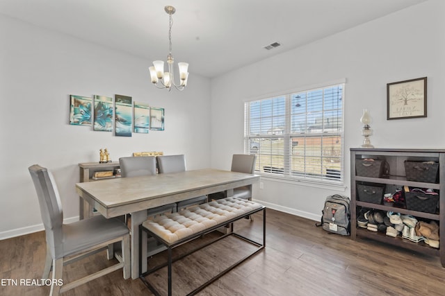 dining room with baseboards, wood finished floors, visible vents, and a notable chandelier