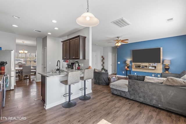 kitchen featuring freestanding refrigerator, a sink, visible vents, and dark brown cabinetry