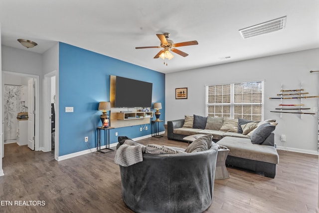 living room featuring a ceiling fan, baseboards, visible vents, and wood finished floors