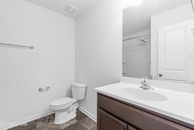 bathroom featuring toilet, vanity, visible vents, baseboards, and walk in shower