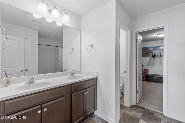 full bathroom with toilet, double vanity, a sink, and visible vents