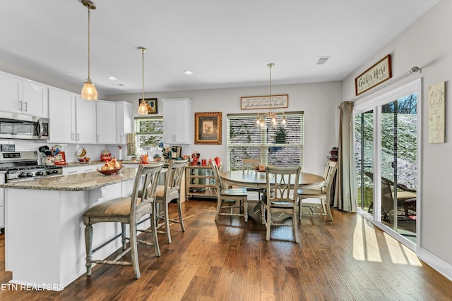 kitchen with hanging light fixtures, decorative backsplash, appliances with stainless steel finishes, white cabinets, and dark stone counters