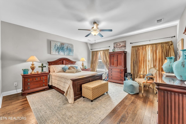 bedroom with dark wood-style flooring, visible vents, ceiling fan, and baseboards