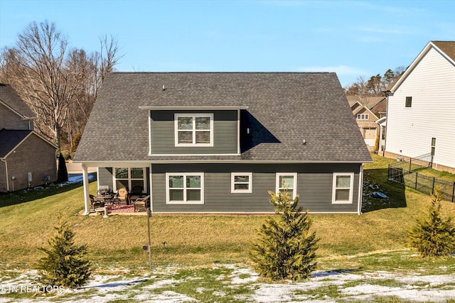 rear view of house with roof with shingles, a lawn, a patio area, and fence