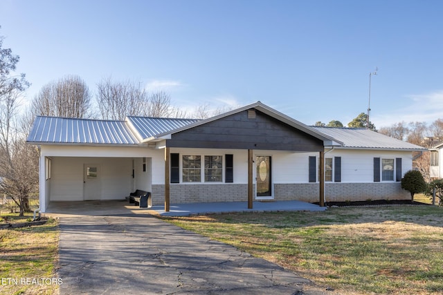 single story home featuring a front yard, metal roof, brick siding, and driveway