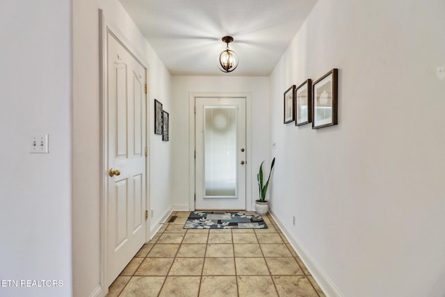 doorway to outside with light tile patterned flooring and baseboards