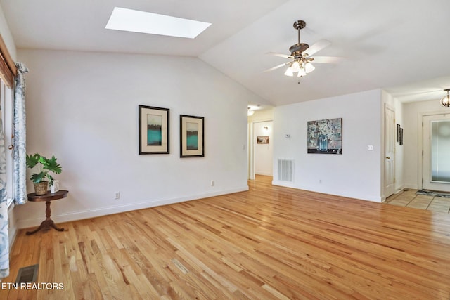 unfurnished living room with vaulted ceiling with skylight, a ceiling fan, visible vents, and light wood-style floors