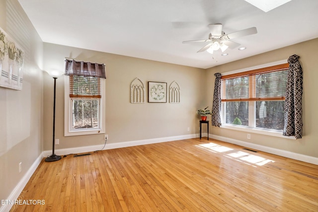 spare room featuring ceiling fan, visible vents, light wood-style flooring, and baseboards