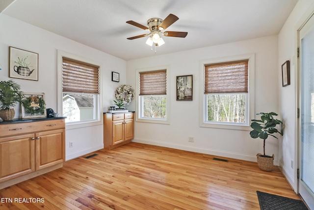 living area with baseboards, visible vents, ceiling fan, and light wood finished floors